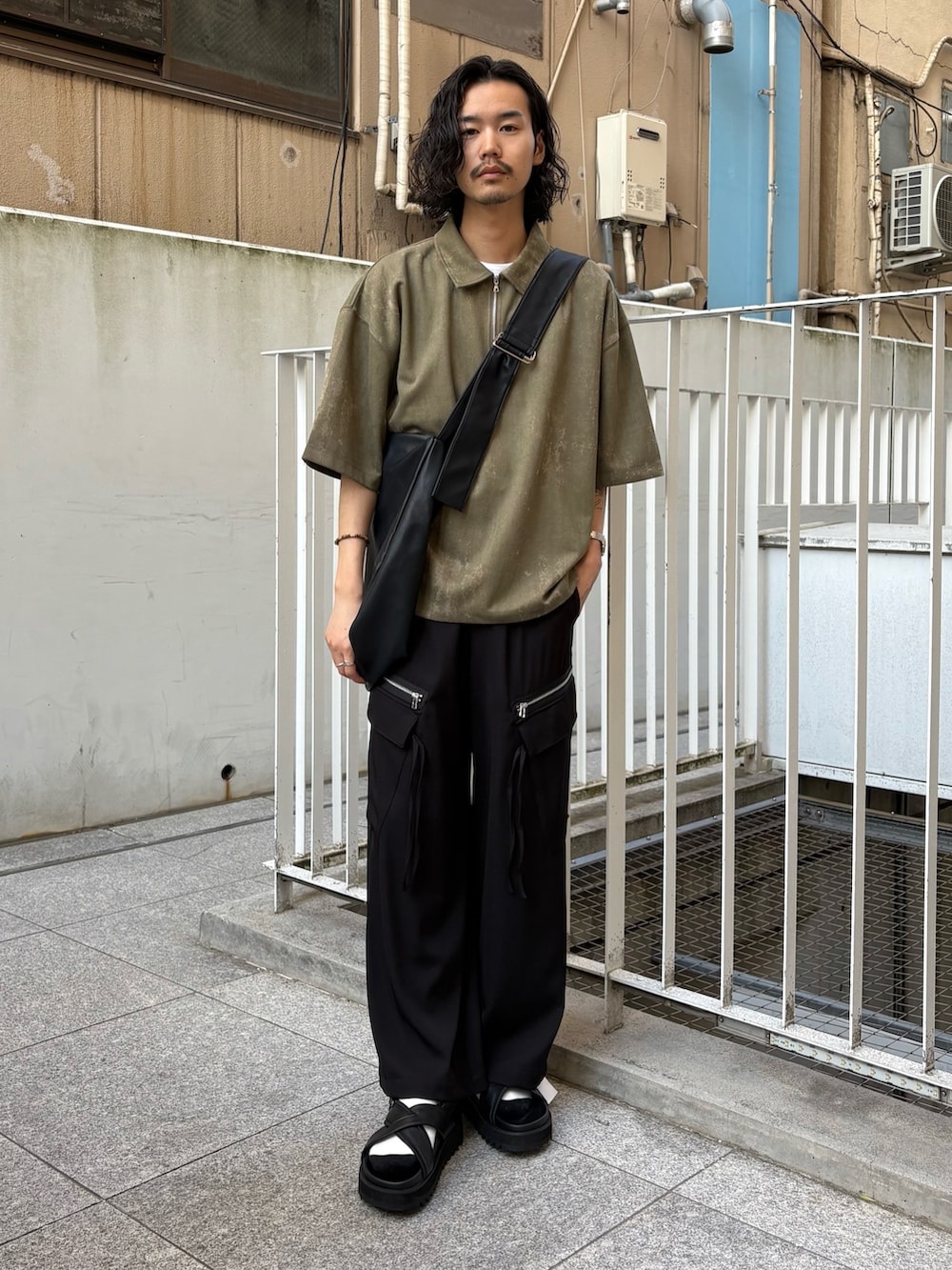グリーン系のポロシャツ、ブラック系のカーゴパンツ、ブラック系のサンダルを着用したメンズの春コーディネートの2枚目の写真