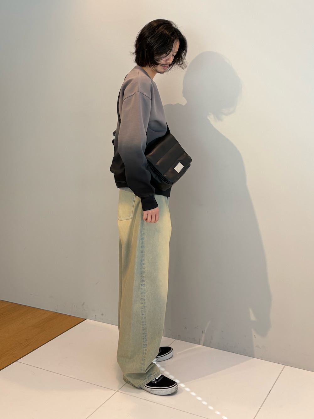 グレー系のTシャツ/カットソー、ブルー系のデニムパンツ、ブラック系のショルダーバッグを着用したメンズの冬コーディネートの2枚目の写真