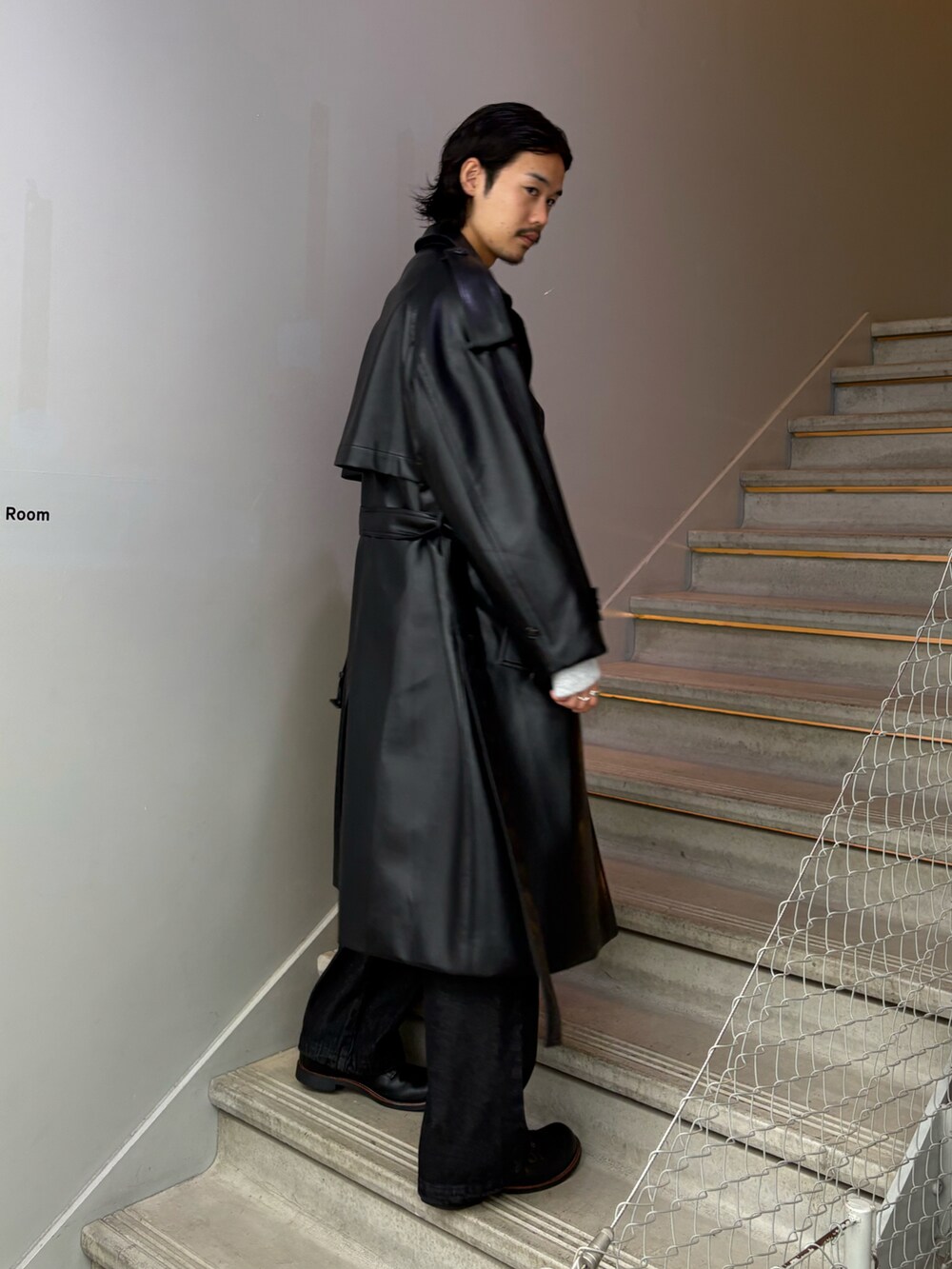 ブラック系のトレンチコート、グレー系のニット/セーターを着用したメンズの秋コーディネートの2枚目の写真