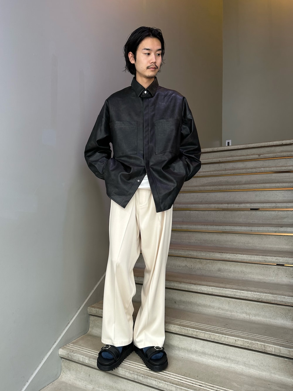 ホワイト系のスラックス、ブラック系のサンダル、ブラック系のショルダーバッグを着用したメンズの夏コーディネートの3枚目の写真