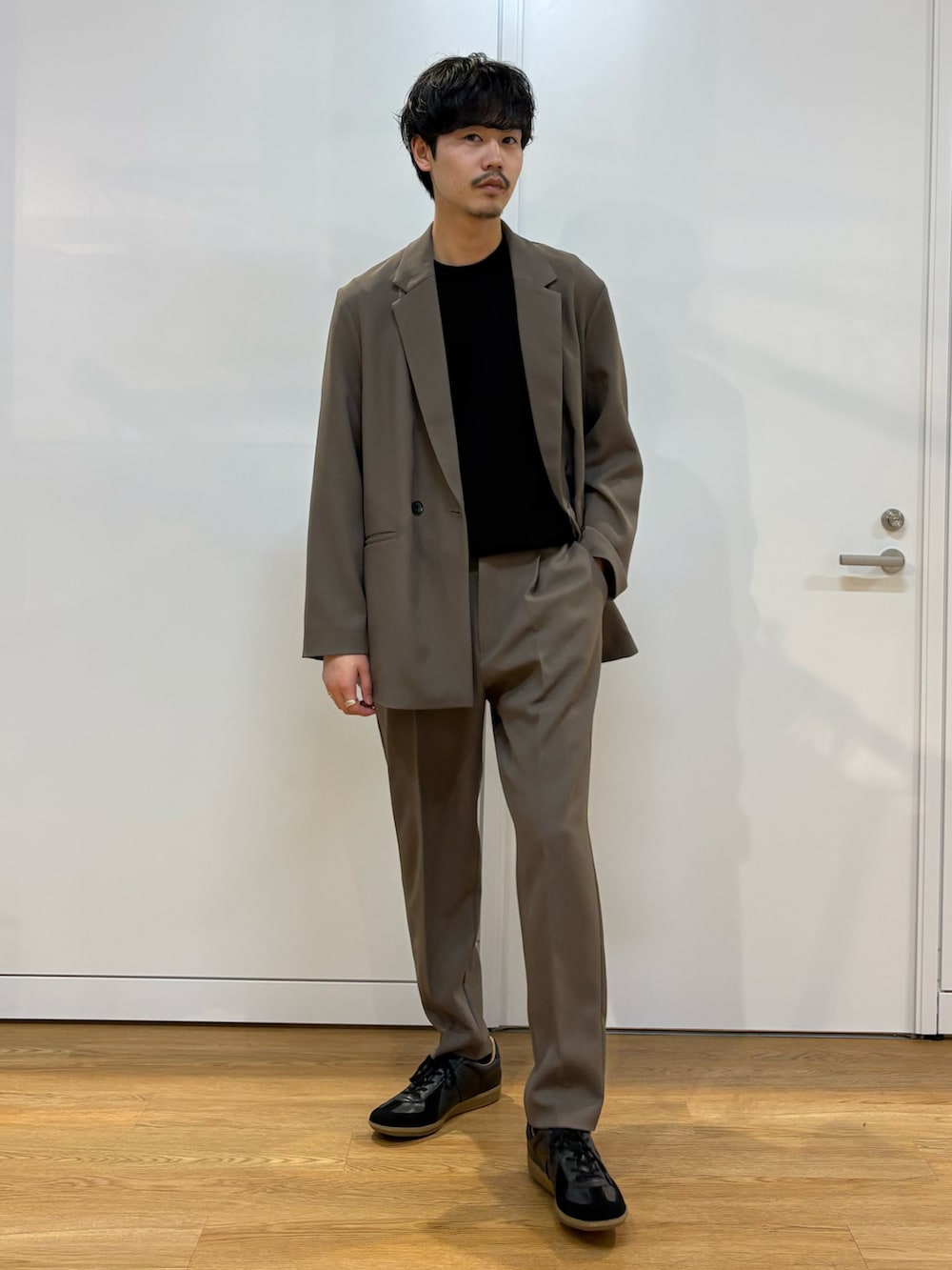 ブラウン系のセットアップ、ブラック系のスニーカーを着用したメンズの春コーディネートの2枚目の写真