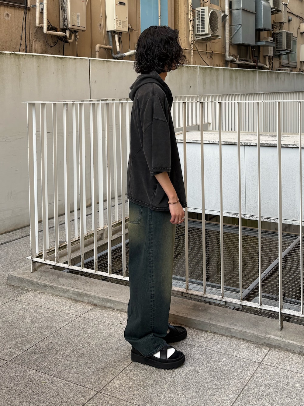 ブラック系のパーカー、ブルー系のデニムパンツ、ブラック系のサンダルを着用したメンズの夏コーディネートの2枚目の写真