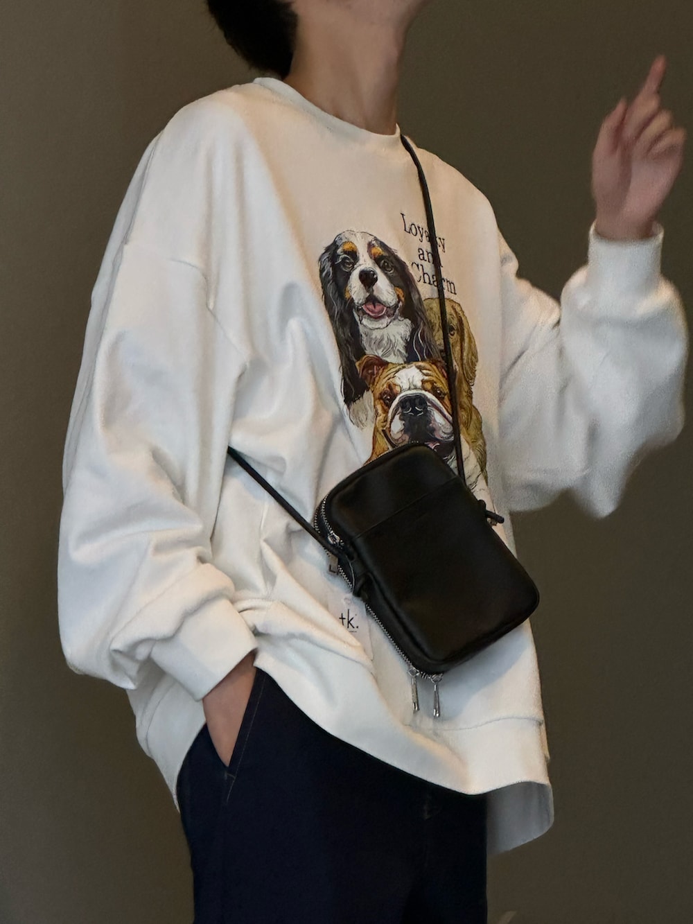 ホワイト系のスウェット、ブラック系のショルダーバッグ、ブルー系のデニムパンツを着用したメンズの冬コーディネートの2枚目の写真