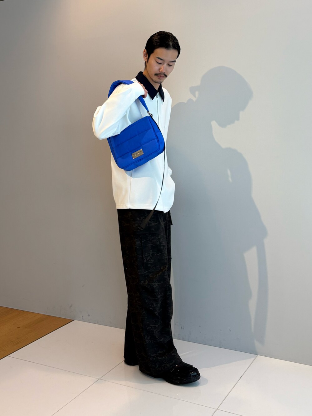 ブラック系のショルダーバッグ、ホワイト系のTシャツ/カットソー、ブラック系のその他シューズを着用したメンズの冬コーディネートの2枚目の写真