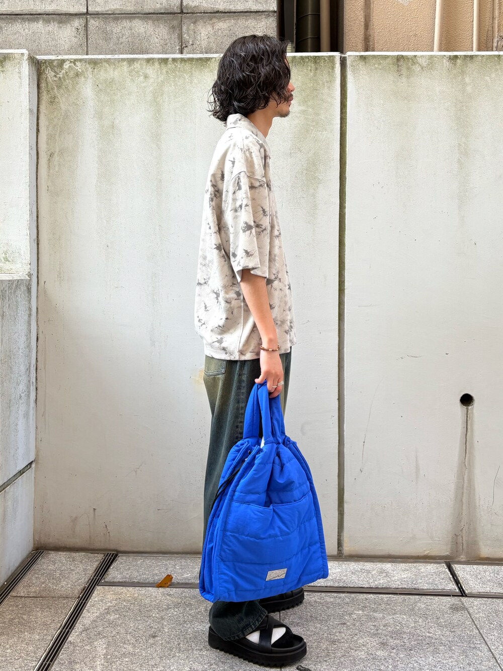 ブラック系のサンダル、ブルー系のトートバッグ、ブルー系のデニムパンツを着用したメンズの春コーディネートの3枚目の写真