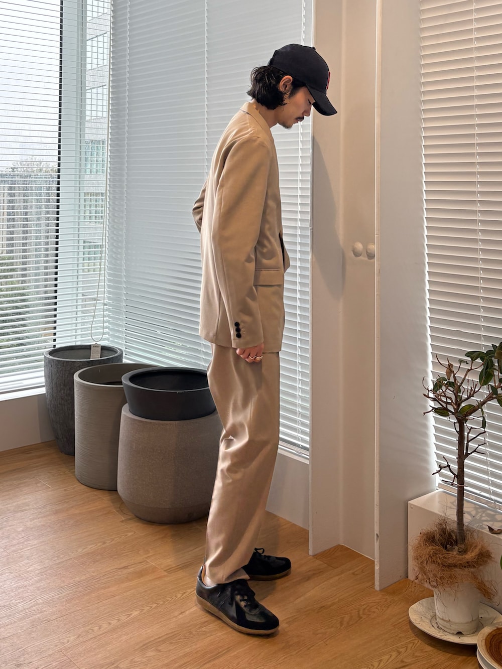 ベージュ系のセットアップ、ブラック系のスニーカーを着用したメンズの春コーディネートの3枚目の写真