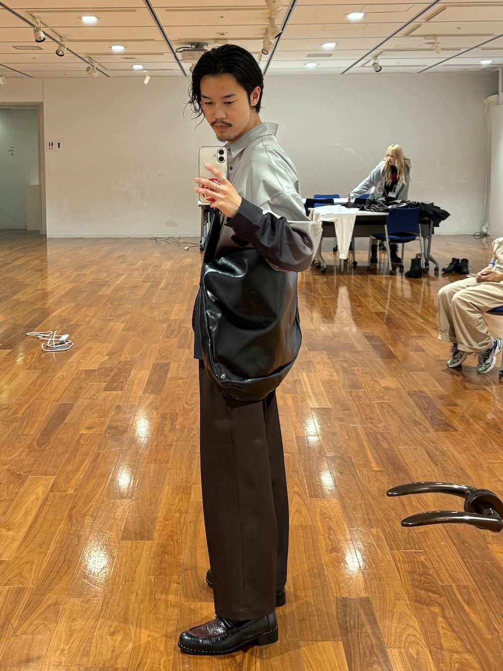 グレー系のシャツ/ブラウス、ブラック系のショルダーバッグ、ブラック系のドレスシューズを着用したメンズの秋コーディネートの2枚目の写真