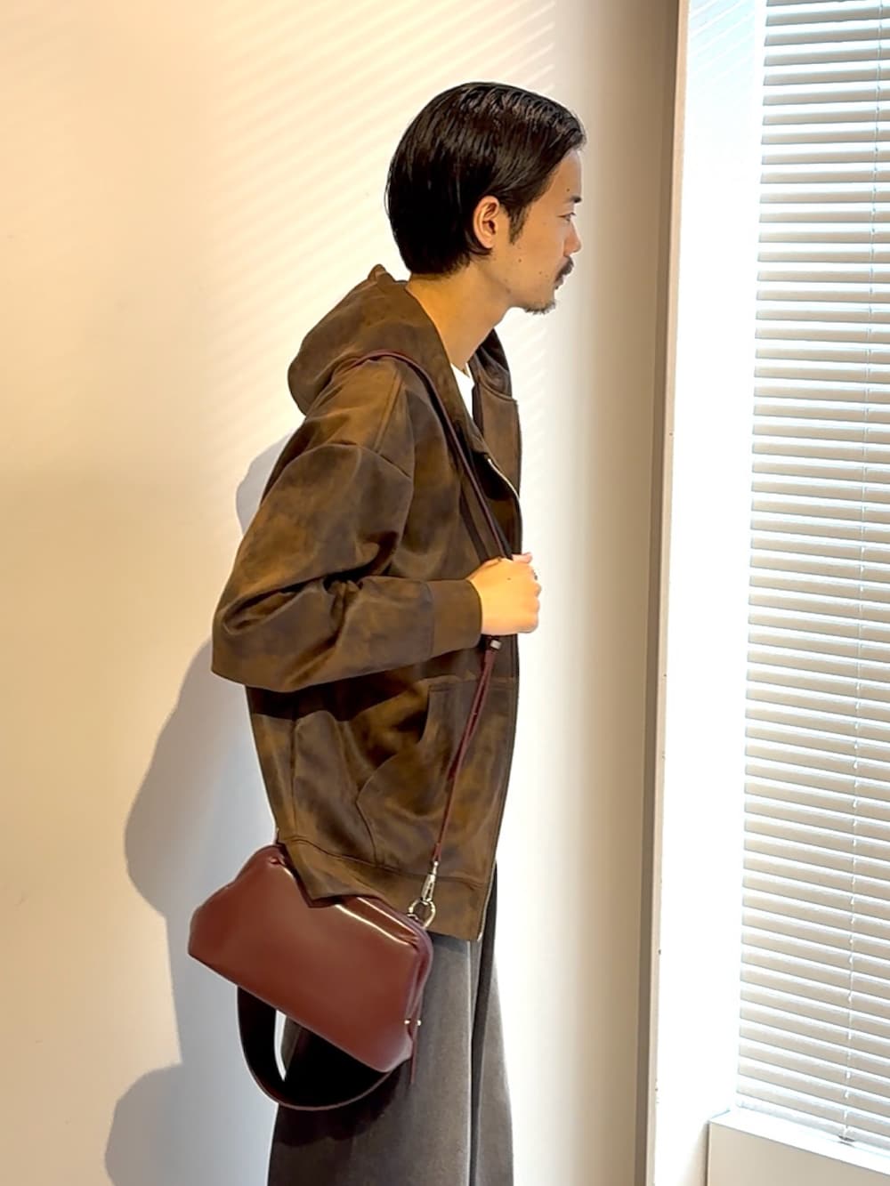 ブラウン系のパーカー、ブラック系のデニムパンツ、レッド系のショルダーバッグを着用したメンズの夏コーディネートの3枚目の写真