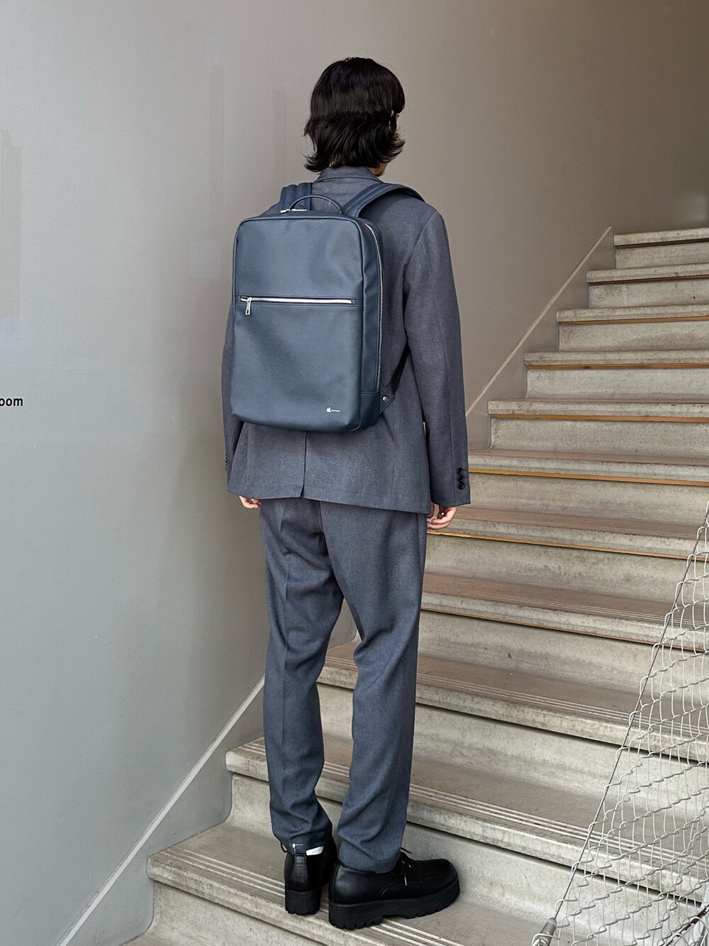 グレー系のセットアップ、ブルー系のバックパック/リュック、ブラック系のその他シューズを着用したメンズの夏コーディネートの2枚目の写真