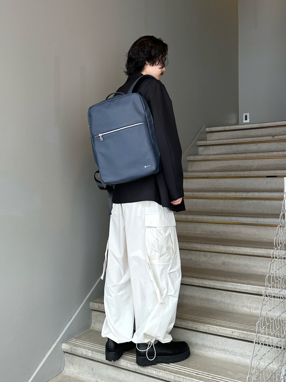 ブラック系のセットアップ、ホワイト系のカーゴパンツ、ブラック系のドレスシューズを着用したメンズの春コーディネートの2枚目の写真