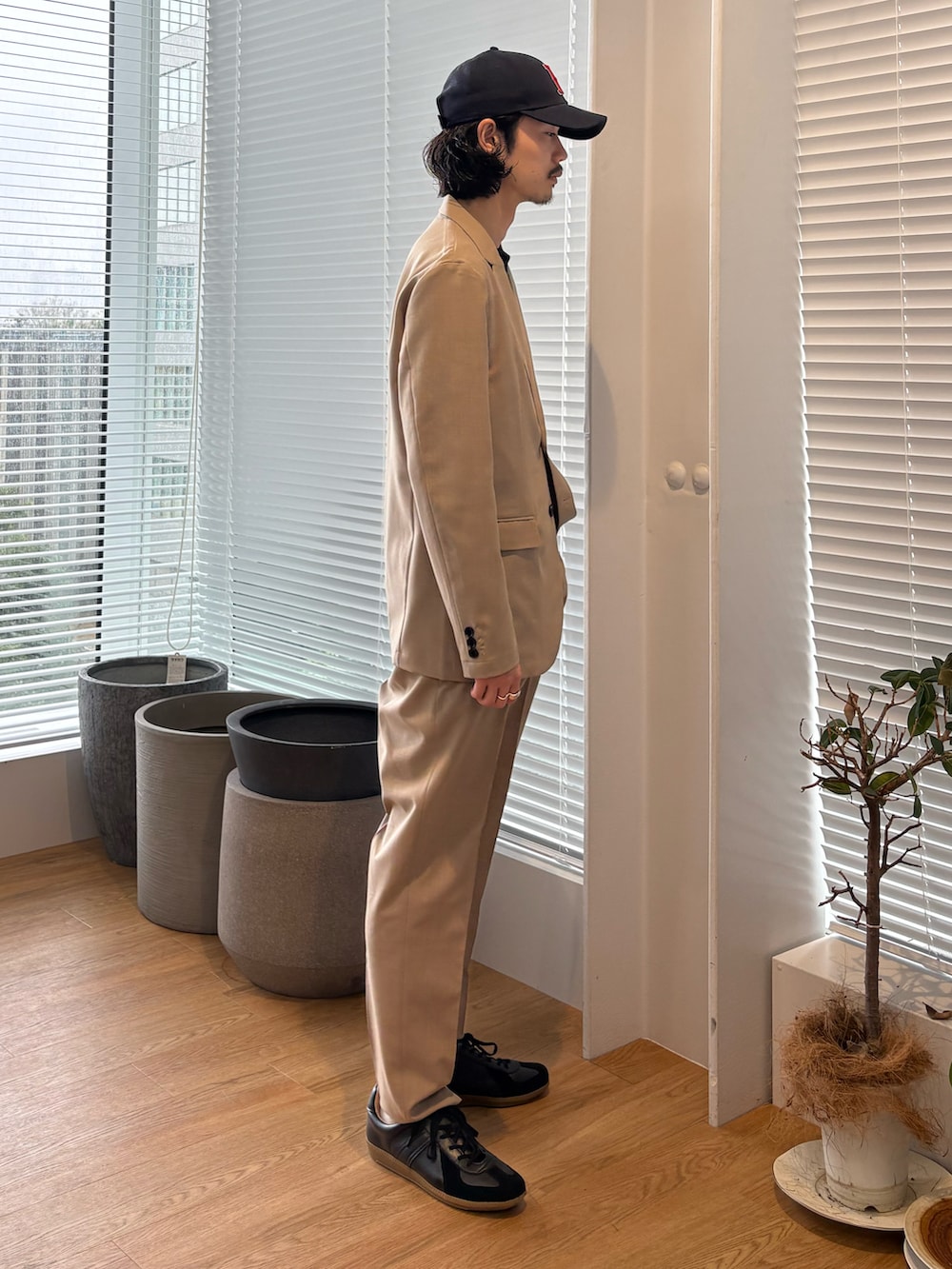 ベージュ系のセットアップ、ブラック系のスニーカーを着用したメンズの春コーディネートの2枚目の写真