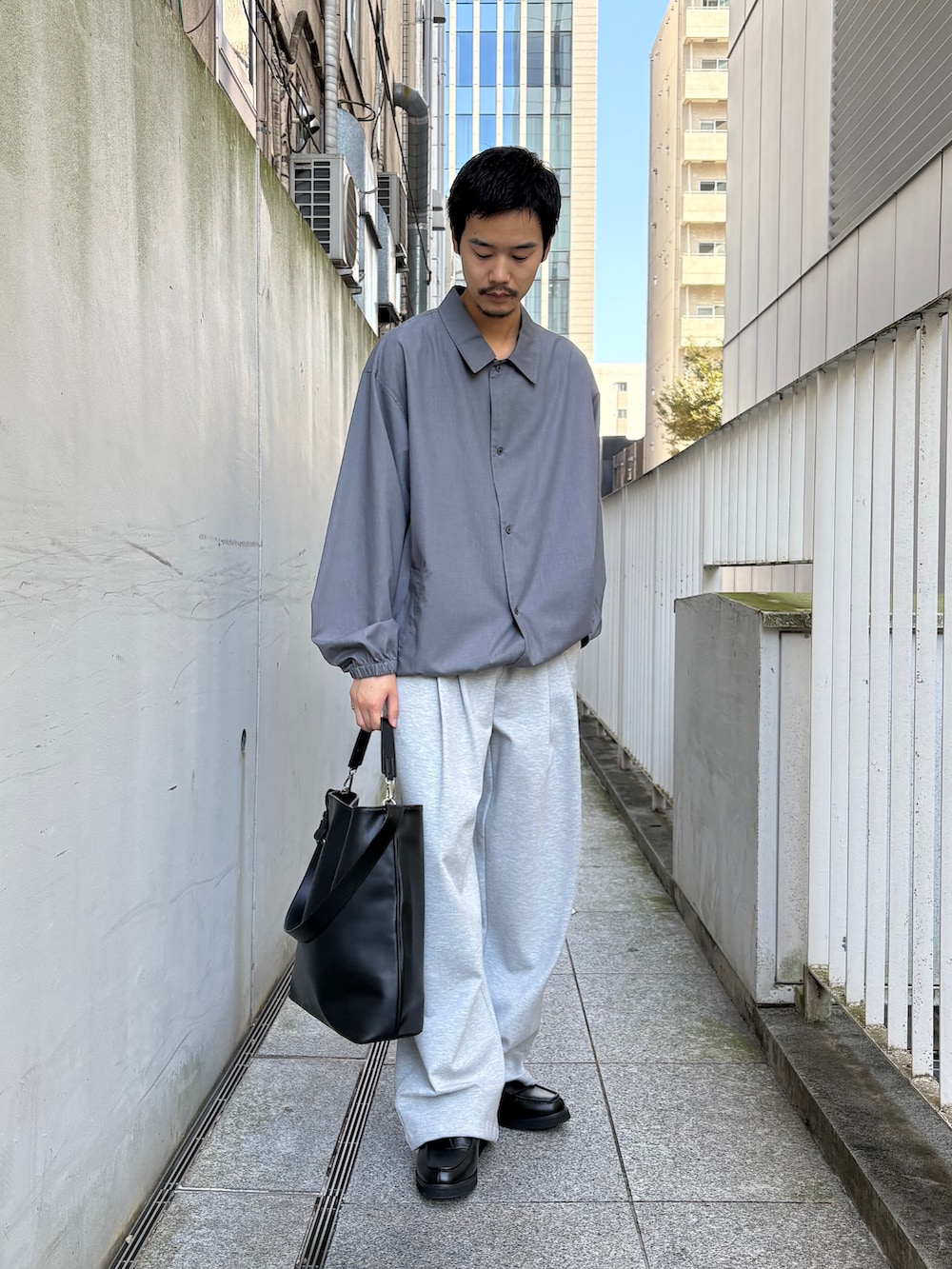 ブラック系のトートバッグ、グレー系のその他パンツ、ブラック系のドレスシューズを着用したメンズの秋コーディネートの2枚目の写真