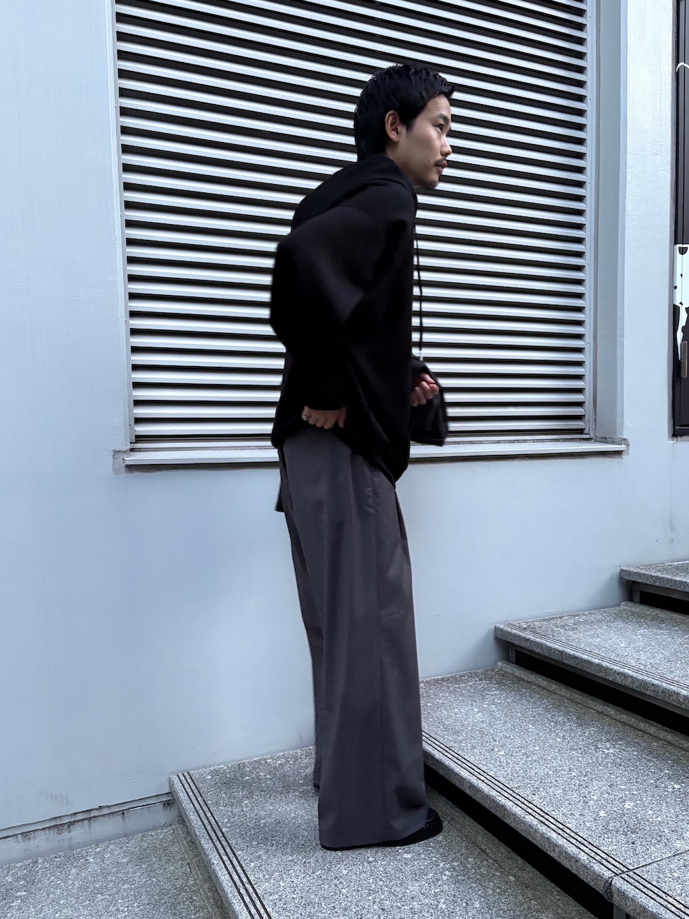 ブラック系のパーカー、グレー系のその他パンツ、ブラック系のドレスシューズを着用したメンズの秋コーディネートの2枚目の写真