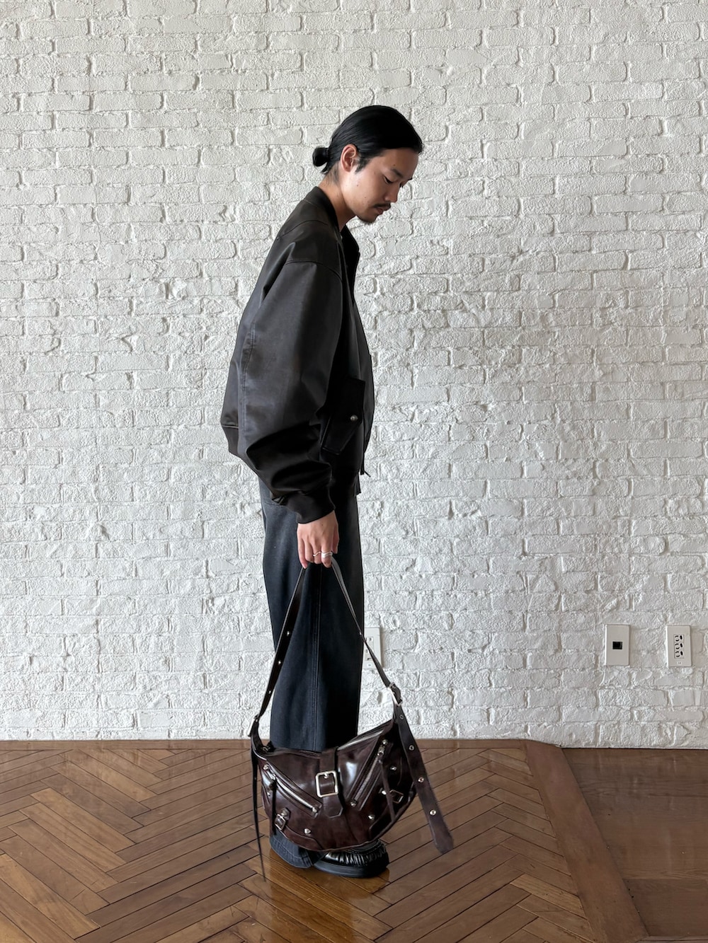 ブラック系のブルゾン、ブラック系のセットアップ、ブラウン系のショルダーバッグを着用したメンズの夏コーディネートの3枚目の写真