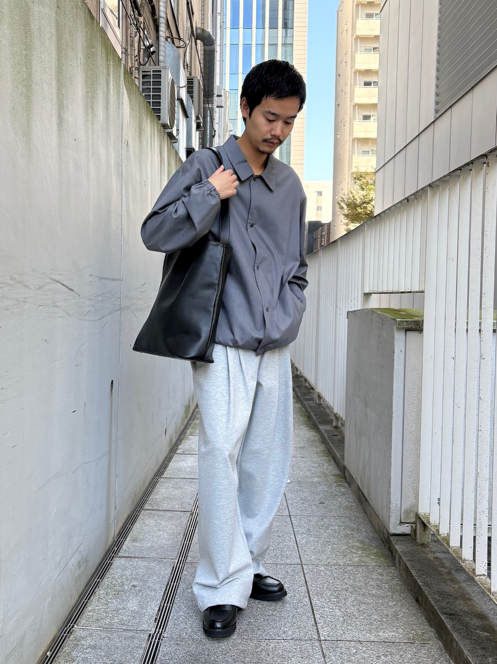 ブラック系のトートバッグ、グレー系のその他パンツ、ブラック系のドレスシューズを着用したメンズの秋コーディネートの3枚目の写真