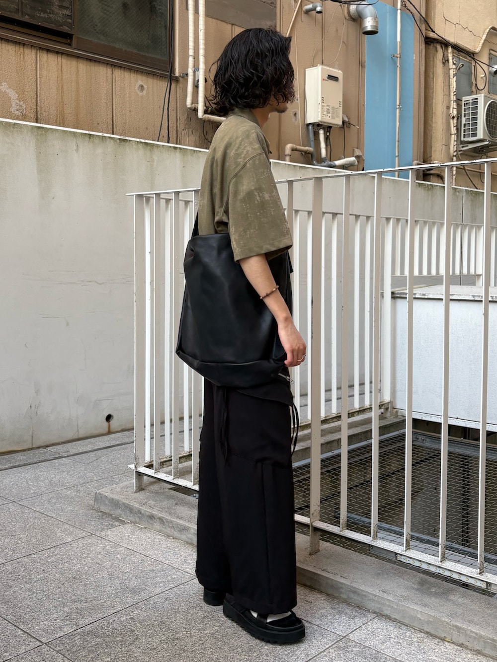 グリーン系のポロシャツ、ブラック系のカーゴパンツ、ブラック系のサンダルを着用したメンズの春コーディネートの3枚目の写真