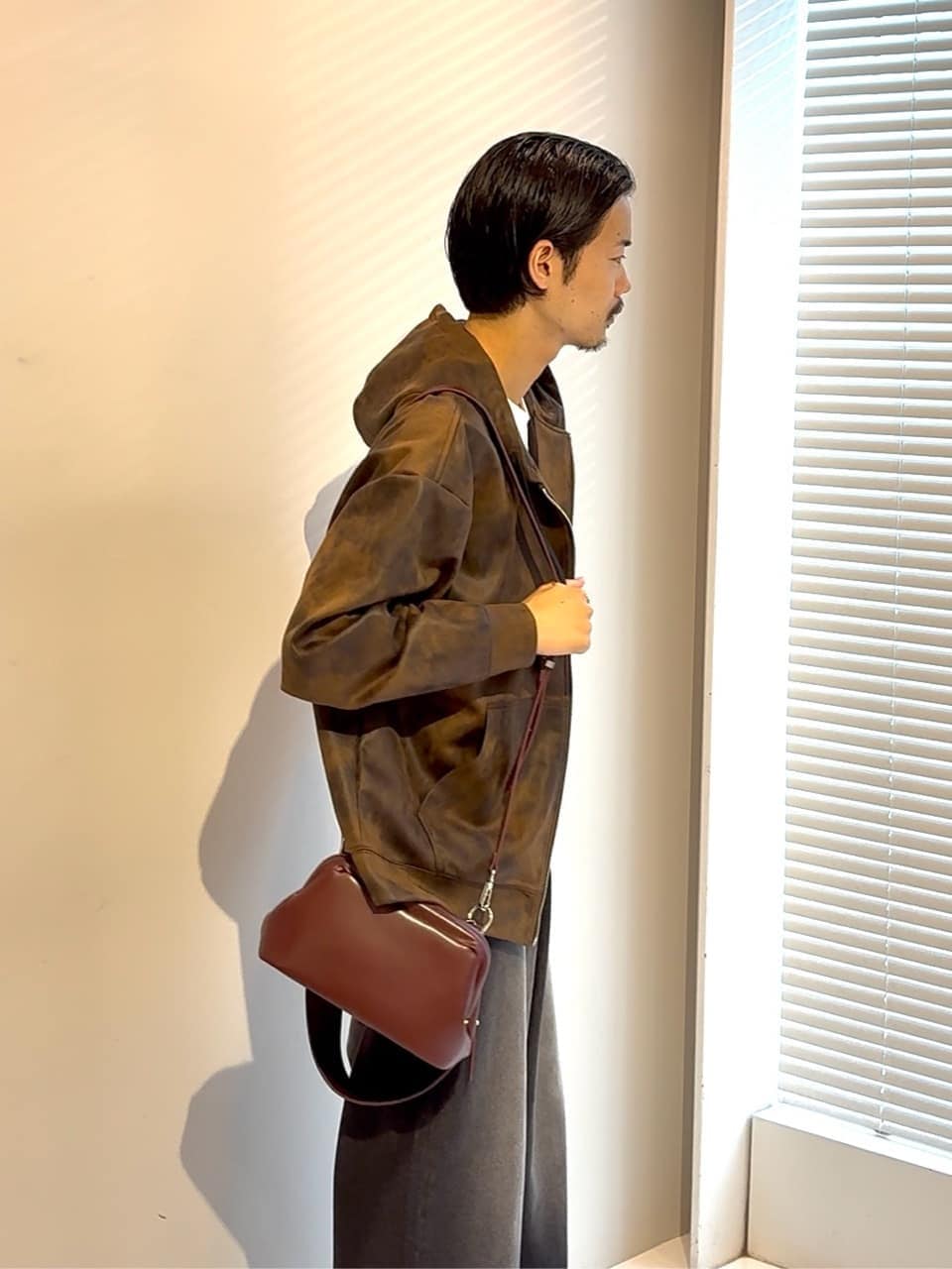 ブラウン系のパーカー、ブルー系のドレスシューズ、レッド系のショルダーバッグを着用したメンズの夏コーディネートの3枚目の写真