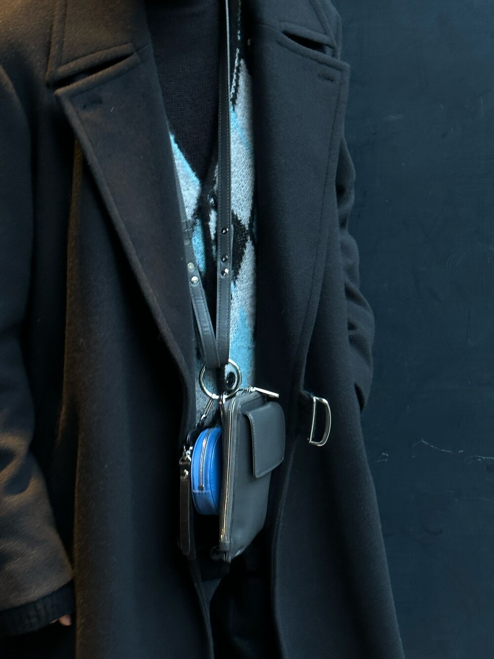 ブラック系のチェスターコート、グレー系のショルダーバッグ、ベージュ系のマフラーを着用したメンズの冬コーディネートの2枚目の写真