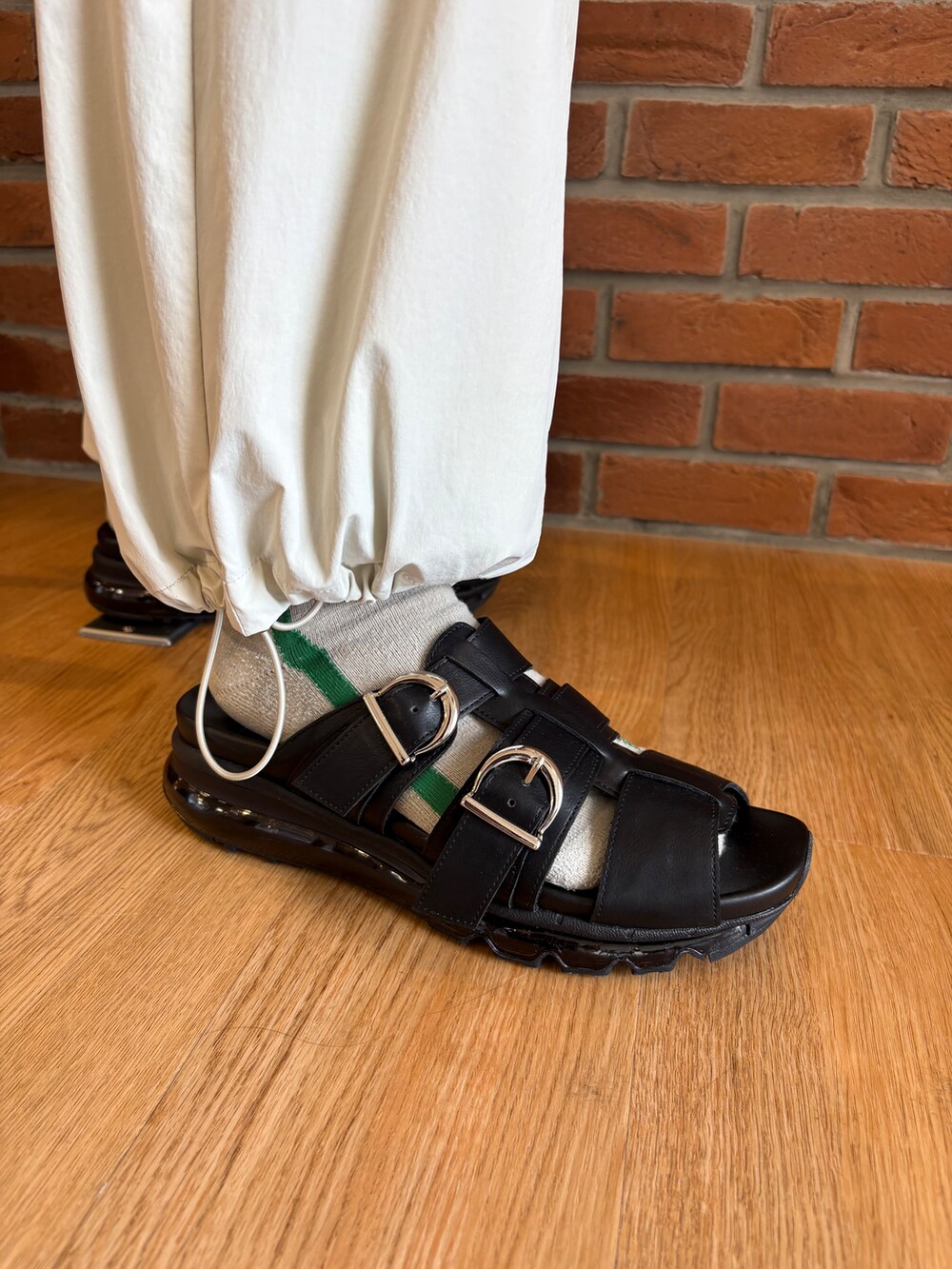 ブラック系のシャツ/ブラウス、ブラウン系のスラックス、ブラック系のサンダルを着用したメンズの春コーディネートの3枚目の写真