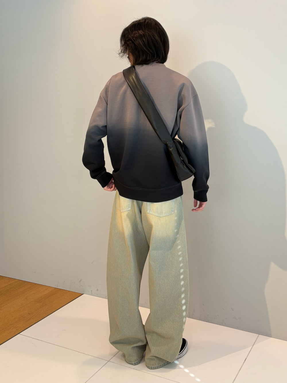 グレー系のTシャツ/カットソー、ブルー系のデニムパンツ、ブラック系のショルダーバッグを着用したメンズの冬コーディネートの3枚目の写真