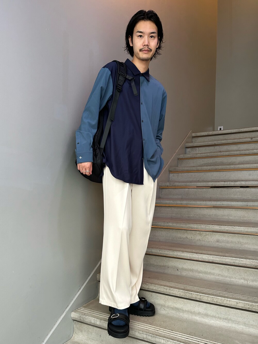 ブラック系のバックパック/リュック、ブラック系のサンダル、ホワイト系のスラックスを着用したメンズの夏コーディネートの2枚目の写真