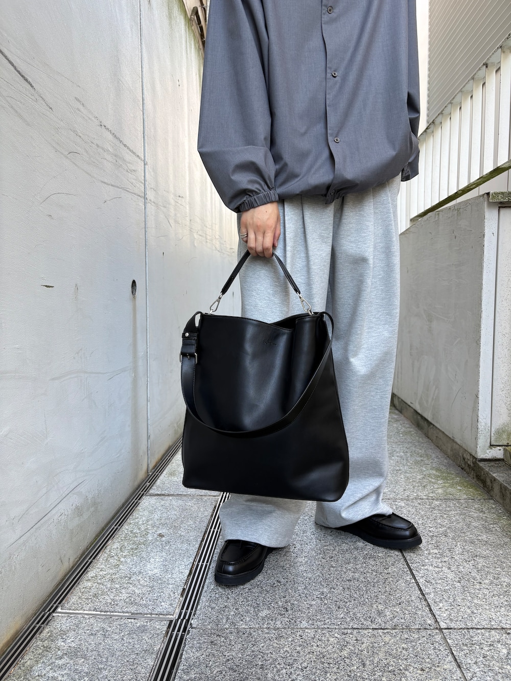 ブラック系のトートバッグ、グレー系のその他パンツ、ブラック系のドレスシューズを着用したメンズの秋コーディネートの4枚目の写真