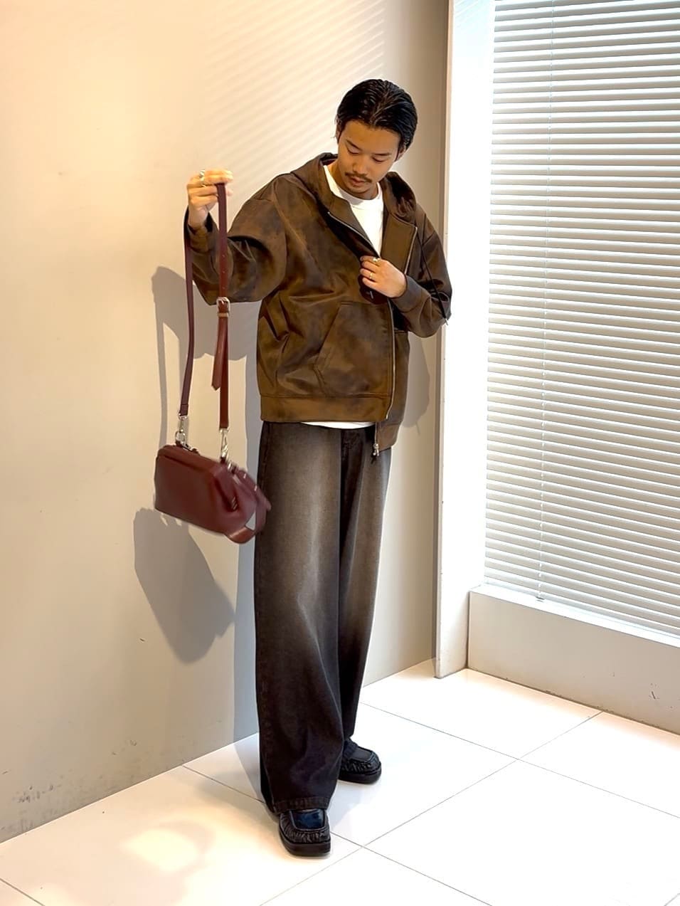 ブラウン系のパーカー、ブルー系のドレスシューズ、レッド系のショルダーバッグを着用したメンズの夏コーディネートの2枚目の写真