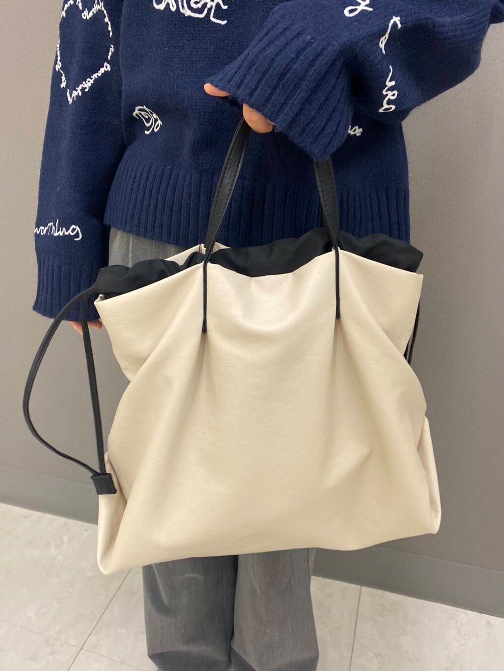ホワイト系のトートバッグ、ブルー系のニット/セーター、ブラック系のブーツを着用したレディースの冬コーディネートの5枚目の写真