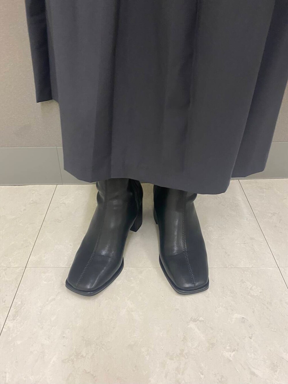 ブラック系のボストンバッグ、ブラック系のブーツ、ホワイト系のニット/セーターを着用したレディースの秋コーディネートの4枚目の写真