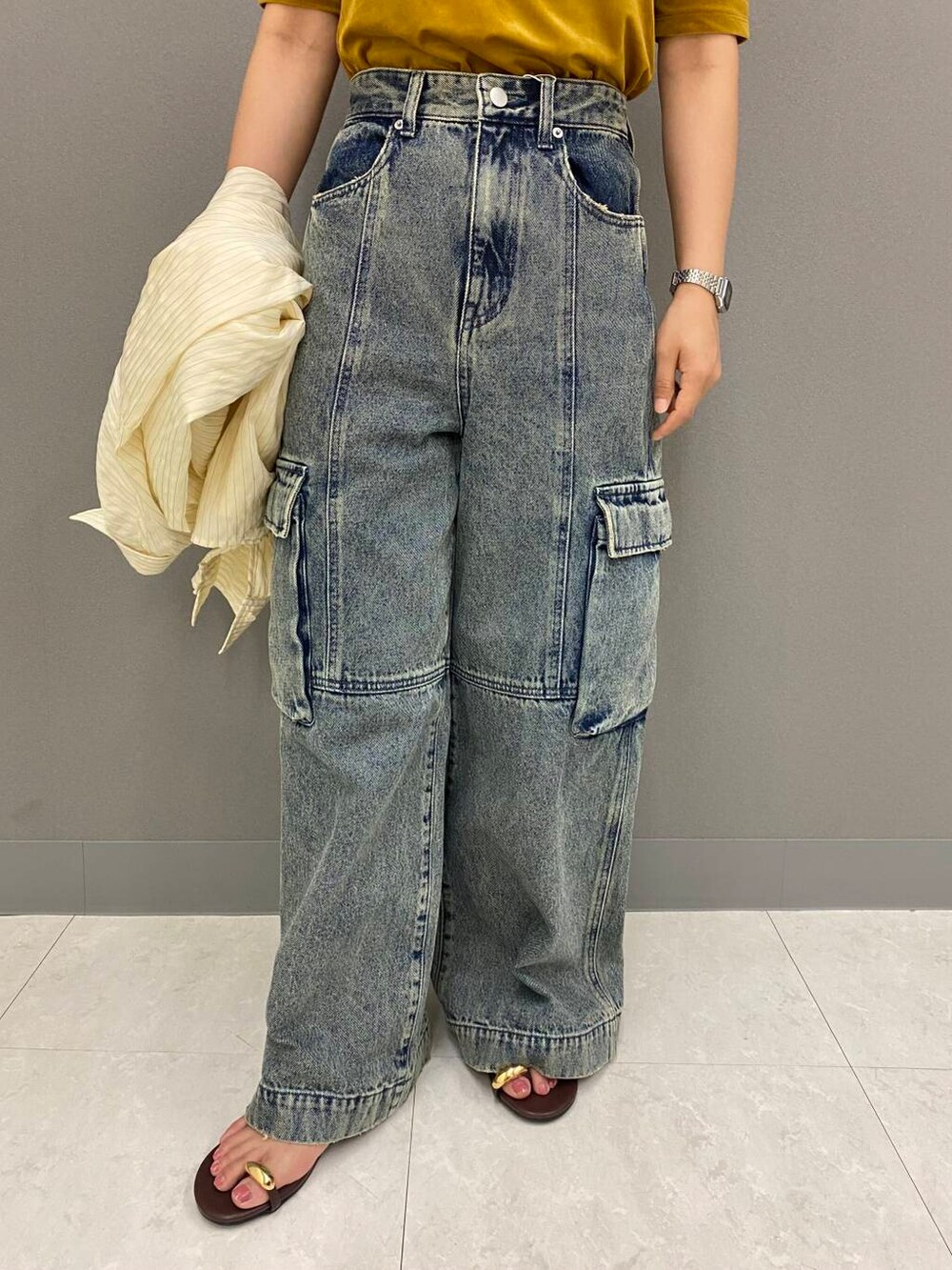 イエロー系のシャツ/ブラウス、ブラウン系のサンダル、グレー系のデニムパンツを着用したレディースの夏コーディネートの3枚目の写真
