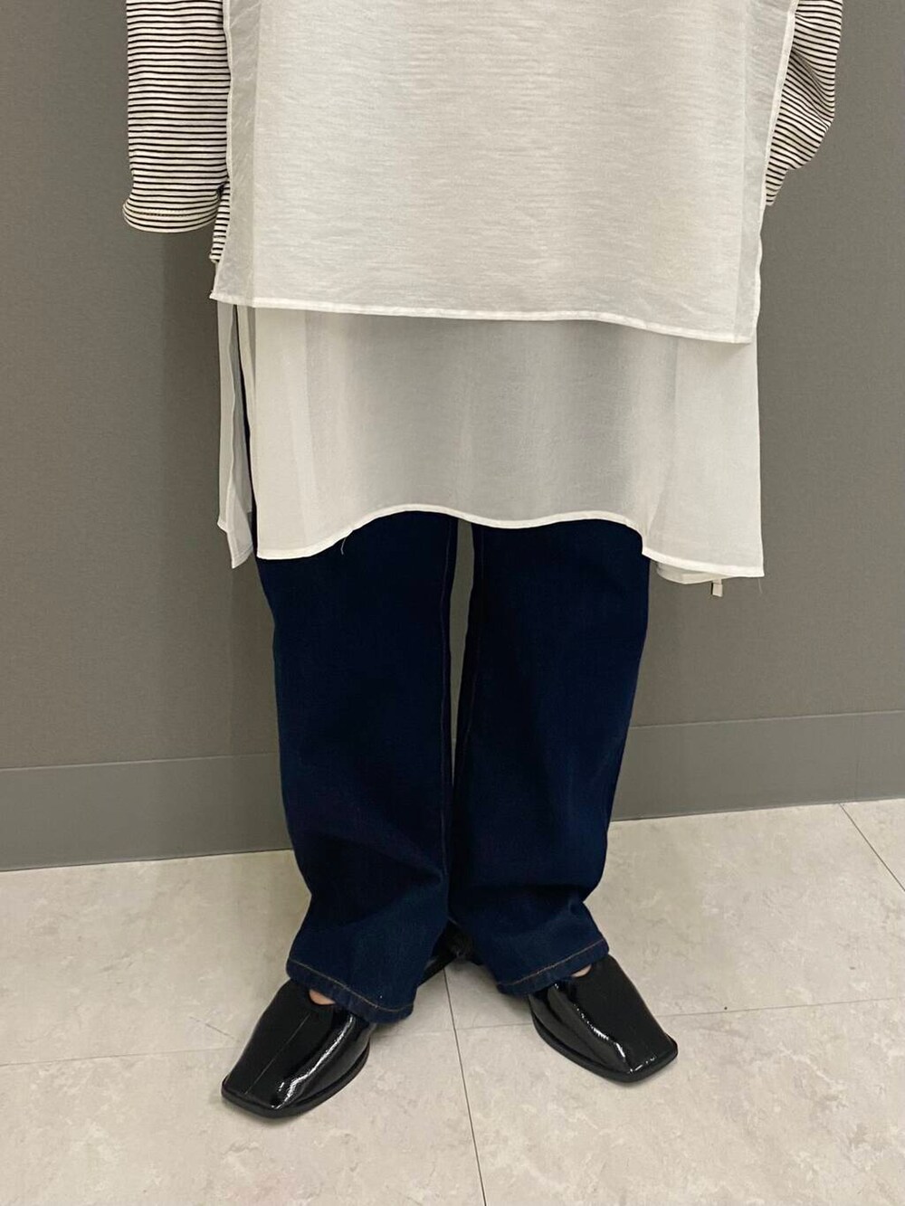ブルー系のデニムパンツ、ブラック系のバレエシューズ、ホワイト系のワンピースを着用したレディースの夏コーディネートの3枚目の写真