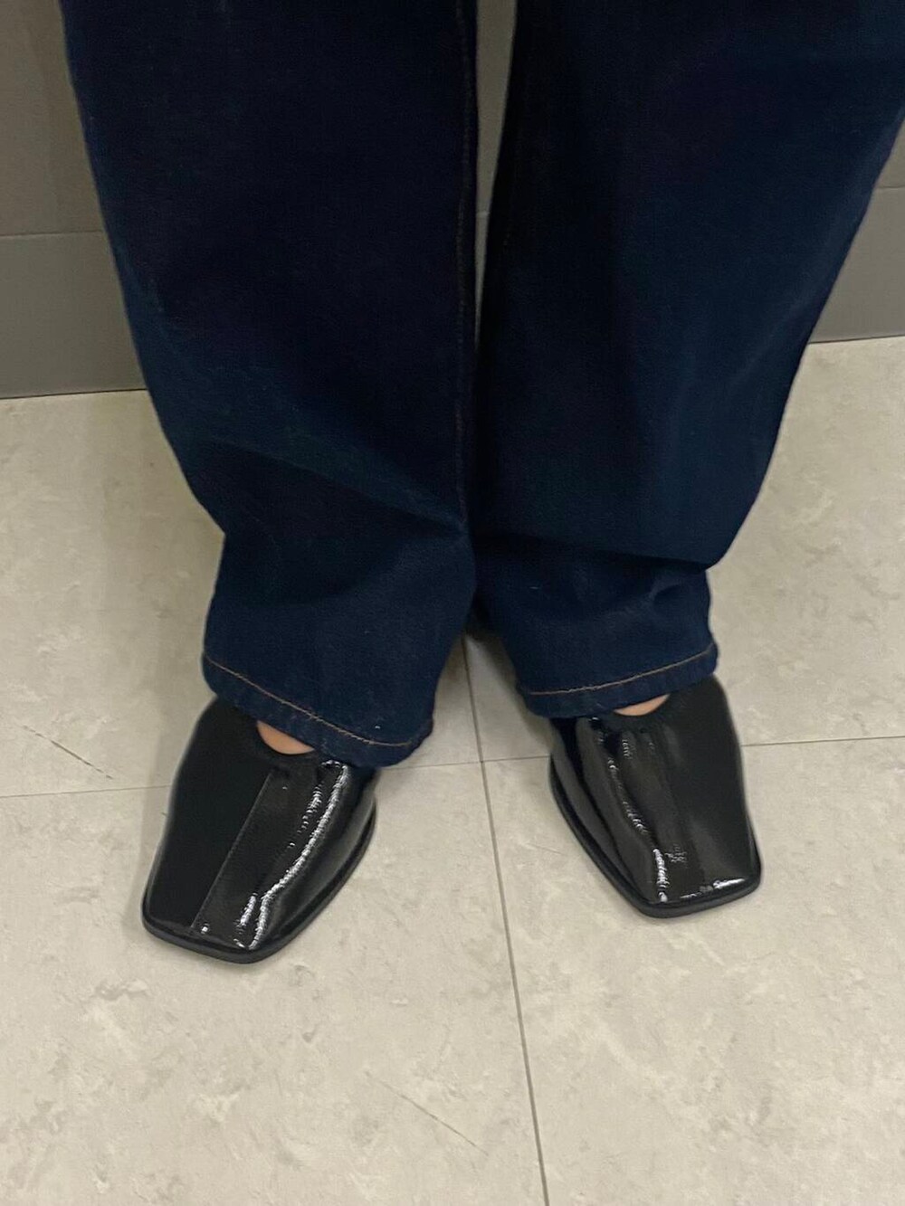 ブルー系のデニムパンツ、ブラック系のバレエシューズ、ホワイト系のワンピースを着用したレディースの夏コーディネートの4枚目の写真