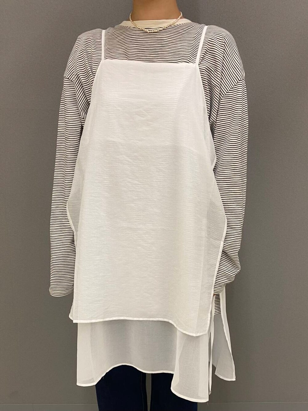 ブルー系のデニムパンツ、ブラック系のバレエシューズ、ホワイト系のワンピースを着用したレディースの夏コーディネートの2枚目の写真