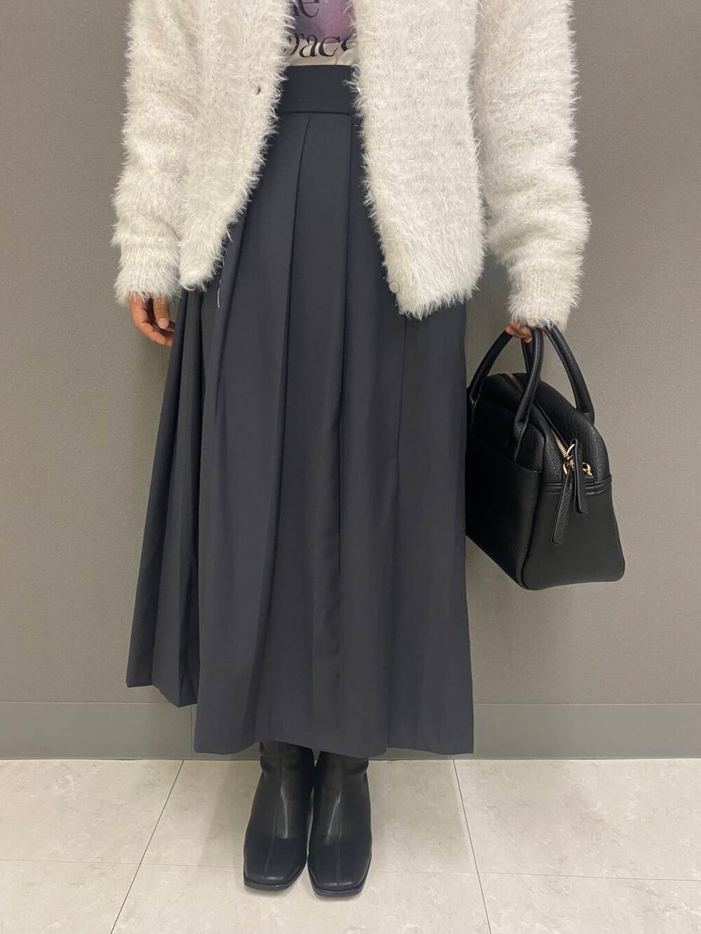 ブラック系のボストンバッグ、ブラック系のブーツ、ホワイト系のニット/セーターを着用したレディースの秋コーディネートの3枚目の写真