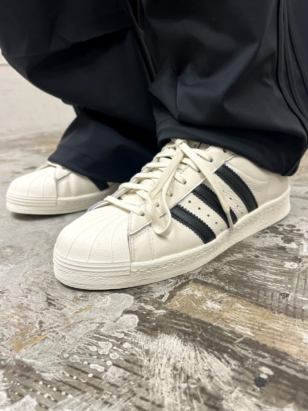 ホワイト系のシューズ、ブラック系のその他パンツ、ホワイト系のTシャツ/カットソーを着用したメンズの春コーディネートの6枚目の写真