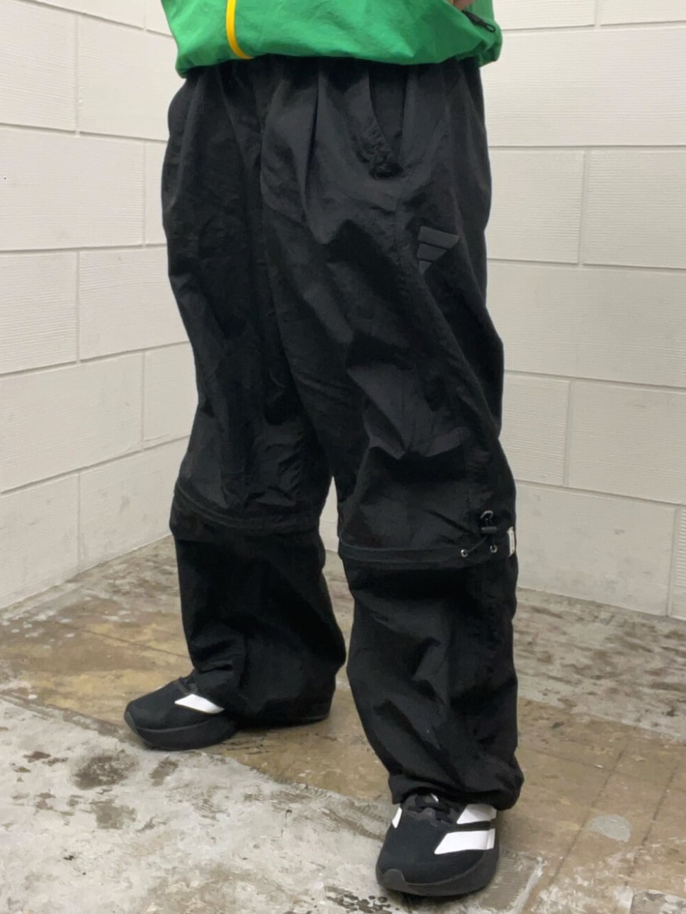 ブラック系のその他パンツ、ブラック系のスニーカー、グリーン系のトップスを着用したメンズの春コーディネートの5枚目の写真