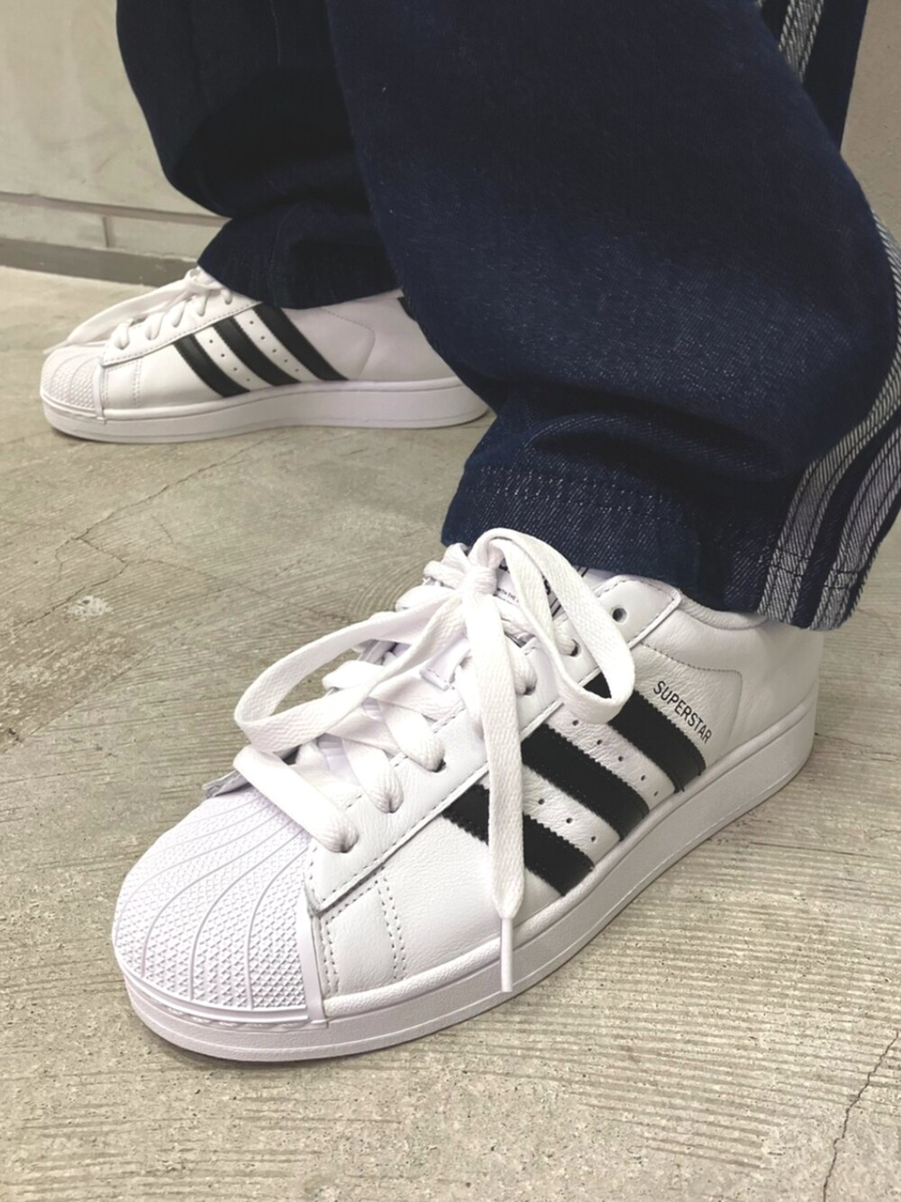 ホワイト系のスニーカー、ブルー系のデニムパンツ、ホワイト系のTシャツ/カットソーを着用したメンズの夏コーディネートの6枚目の写真