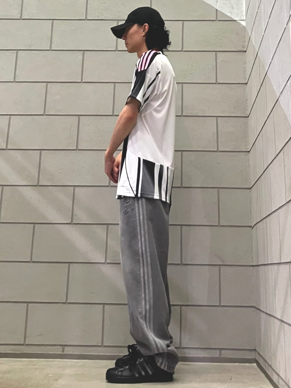 ブラック系のスニーカー、ホワイト系のTシャツ/カットソー、ブルー系のデニムパンツを着用したメンズの夏コーディネートの2枚目の写真
