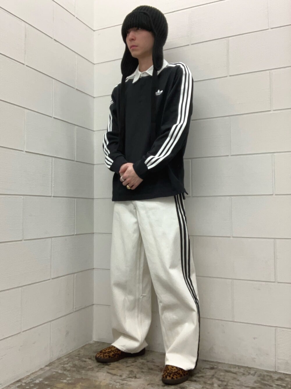 ベージュ系のスニーカー、ブラック系のポロシャツを着用したメンズの春コーディネートの2枚目の写真