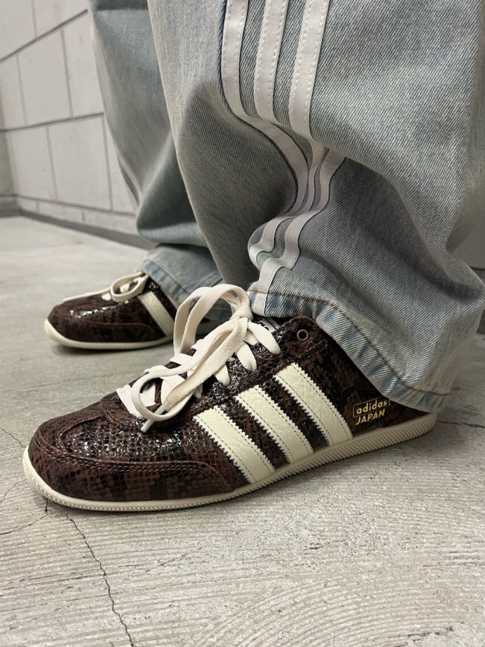 ブラウン系のスニーカー、ブラウン系のジャージ、ブルー系のデニムパンツを着用したメンズの秋コーディネートの6枚目の写真