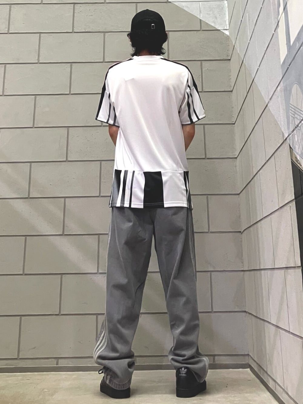 ブラック系のスニーカー、ホワイト系のTシャツ/カットソー、ブルー系のデニムパンツを着用したメンズの夏コーディネートの3枚目の写真