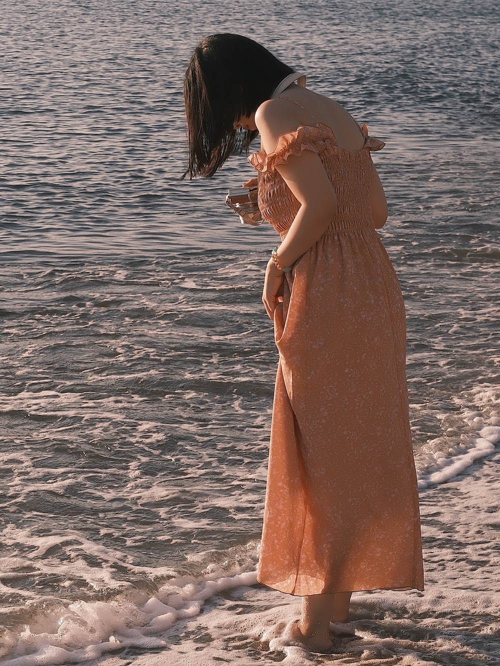 オレンジ系のワンピースを着用したレディースの夏コーディネートの2枚目の写真