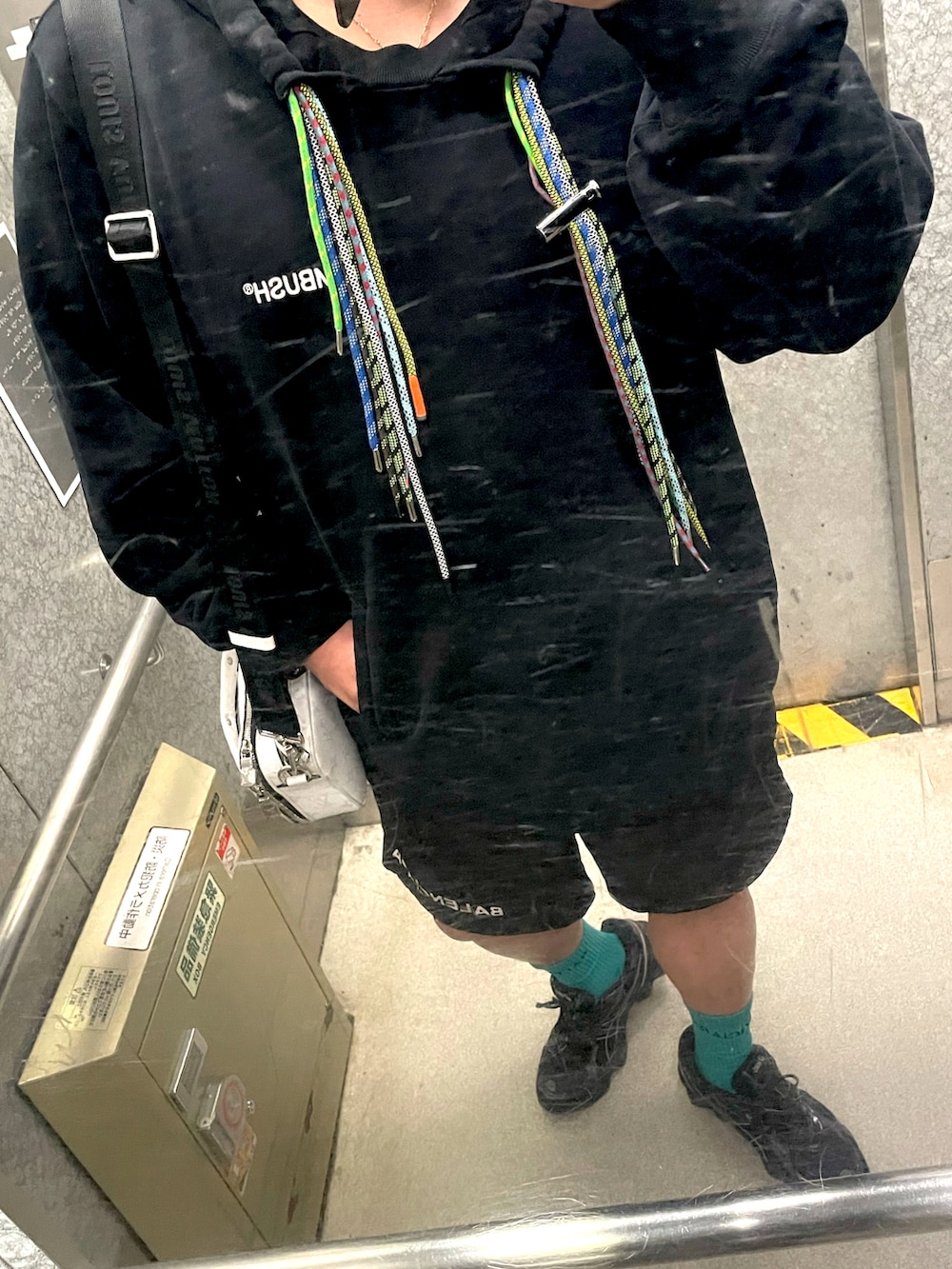 ブラック系のパーカー、ブラック系のその他パンツ、ホワイト系のメッセンジャーバッグを着用したメンズの春コーディネートの2枚目の写真