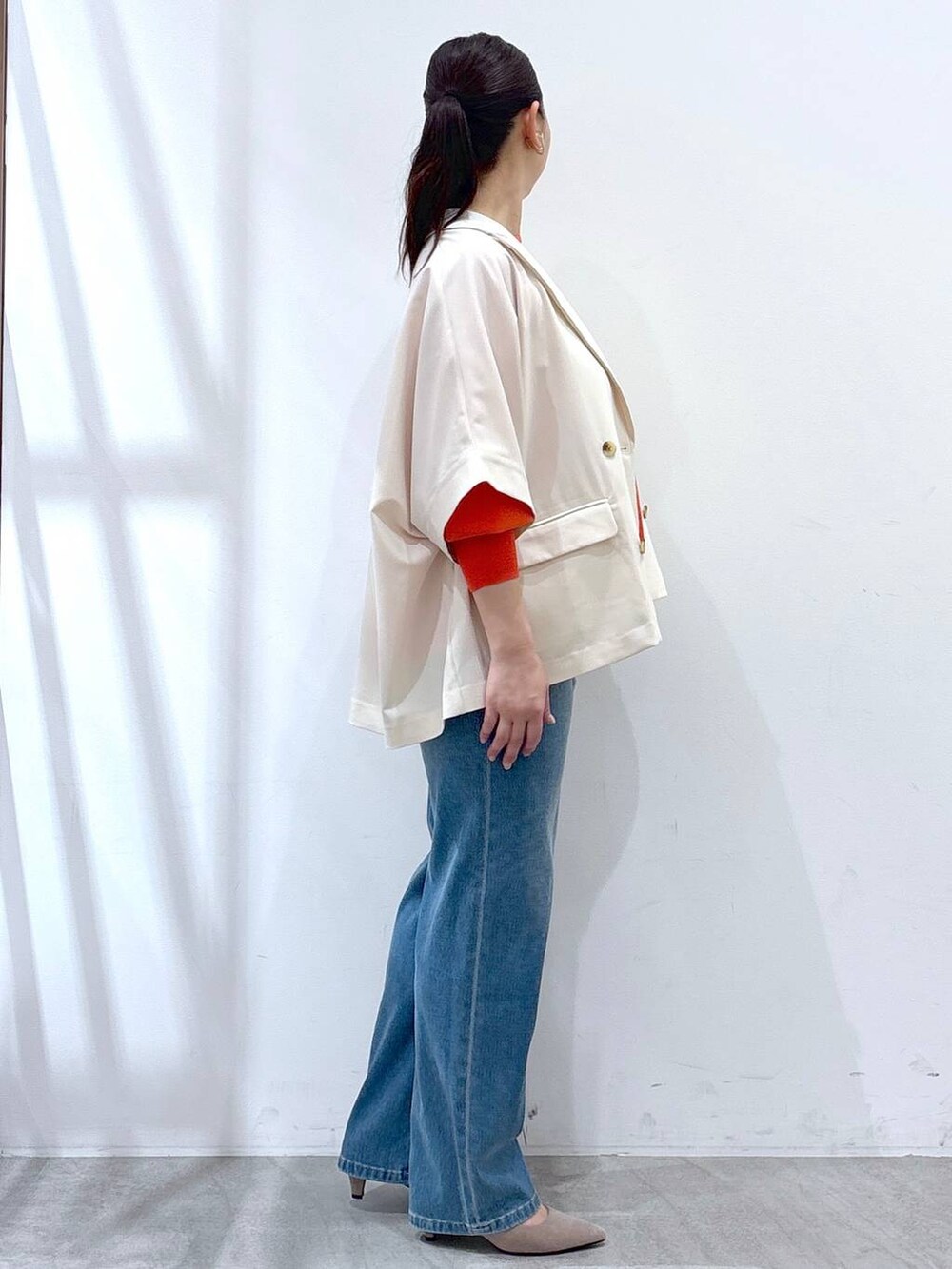 ベージュ系のパンプス、ブルー系のデニムパンツ、オレンジ系のニット/セーターを着用したレディースの春コーディネートの5枚目の写真