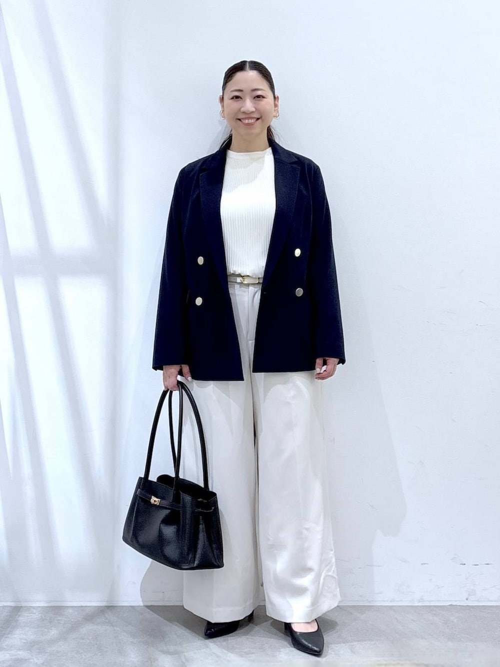 ホワイト系のスラックス、ホワイト系のシャツ/ブラウス、ブラック系のハンドバッグを着用したレディースの冬コーディネートの2枚目の写真