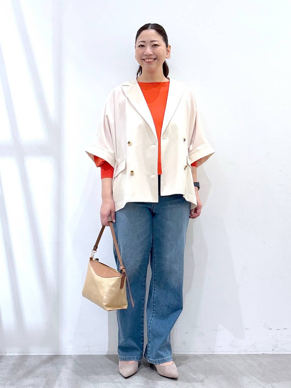 ベージュ系のパンプス、ブルー系のデニムパンツ、オレンジ系のニット/セーターを着用したレディースの春コーディネートの2枚目の写真