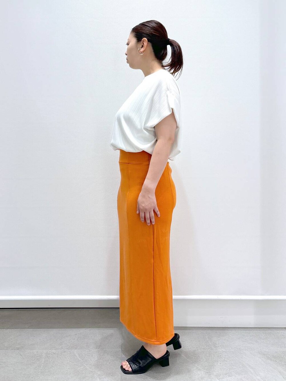 ブラック系のサンダル、ホワイト系のTシャツ/カットソー、オレンジ系のスカートを着用したレディースの春コーディネートの3枚目の写真