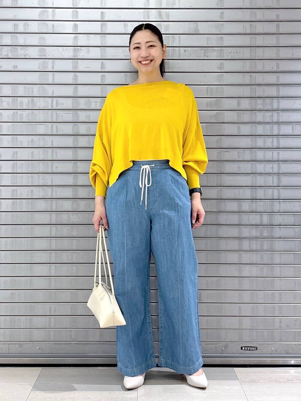 ホワイト系のハンドバッグ、イエロー系のニット/セーターを着用したレディースの春コーディネートの2枚目の写真