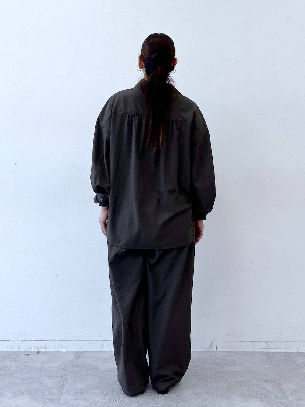 ブラック系のハンドバッグ、ブラック系のパンプス、ブラウン系のシャツ/ブラウスを着用したレディースの冬コーディネートの3枚目の写真