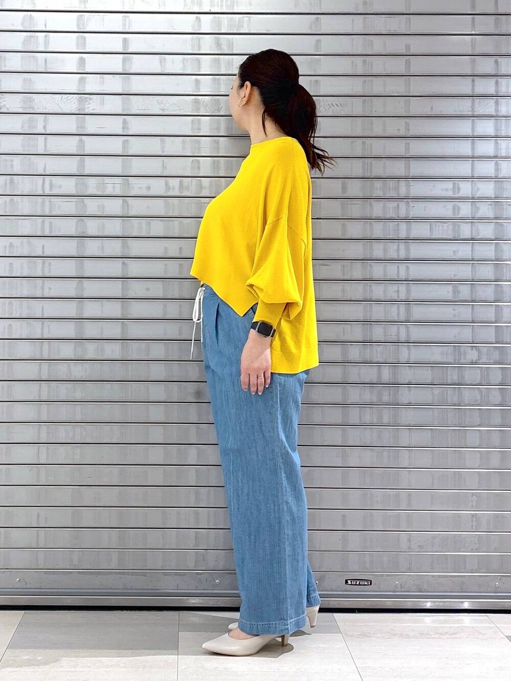 ホワイト系のハンドバッグ、イエロー系のニット/セーターを着用したレディースの春コーディネートの3枚目の写真